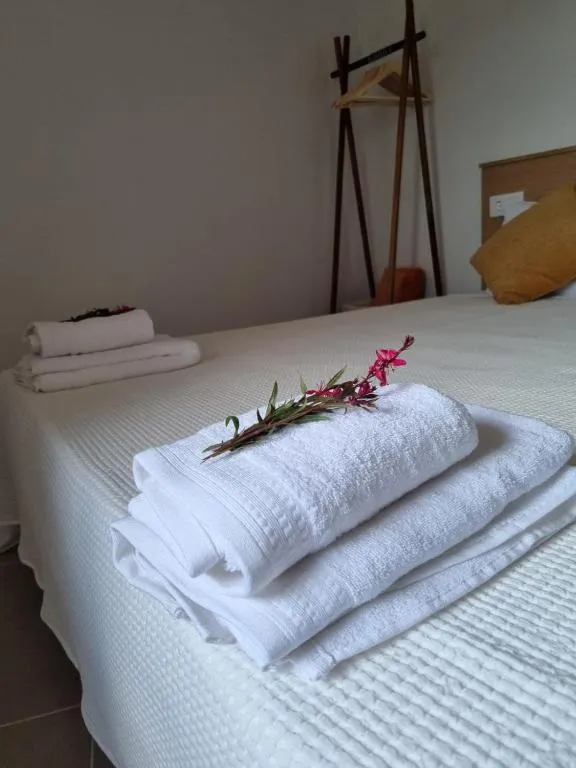 Tovalloles blanques doblegades sobre el llit amb una flor rosa de benvinguda