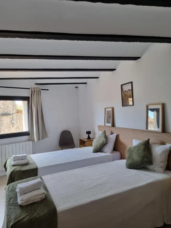 Habitació amb dos llits individuals, tèxtil verd oliva i finestra al carrer