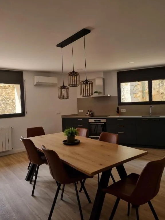 Taula de fusta massissa per a sis amb làmpades de vímet i la cuina al fons