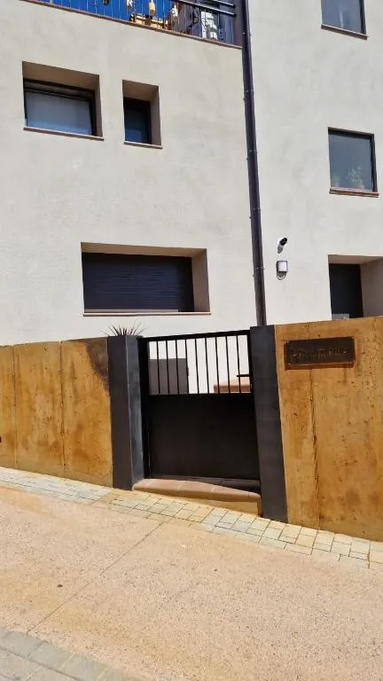 Portal d’entrada d’acer corten i reixa negra vist des del carrer