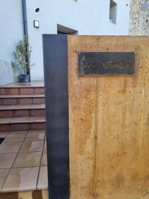 Rètol de llautó amb el nom «Les Ametlles» sobre el mur d’acer corten de l’entrada