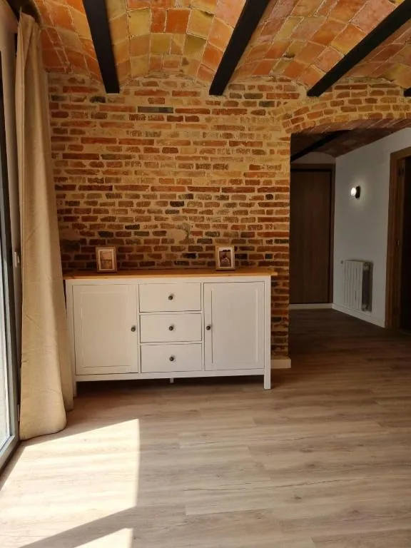 Sala amb paret de maó antic, volta de rajola i aparador blanc