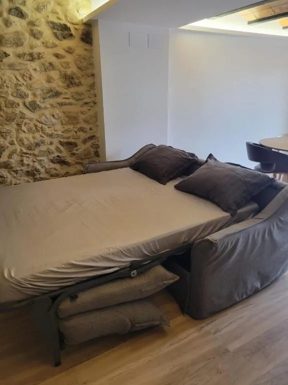 El sofà llit obert amb el mur de pedra seca il·luminat al darrere